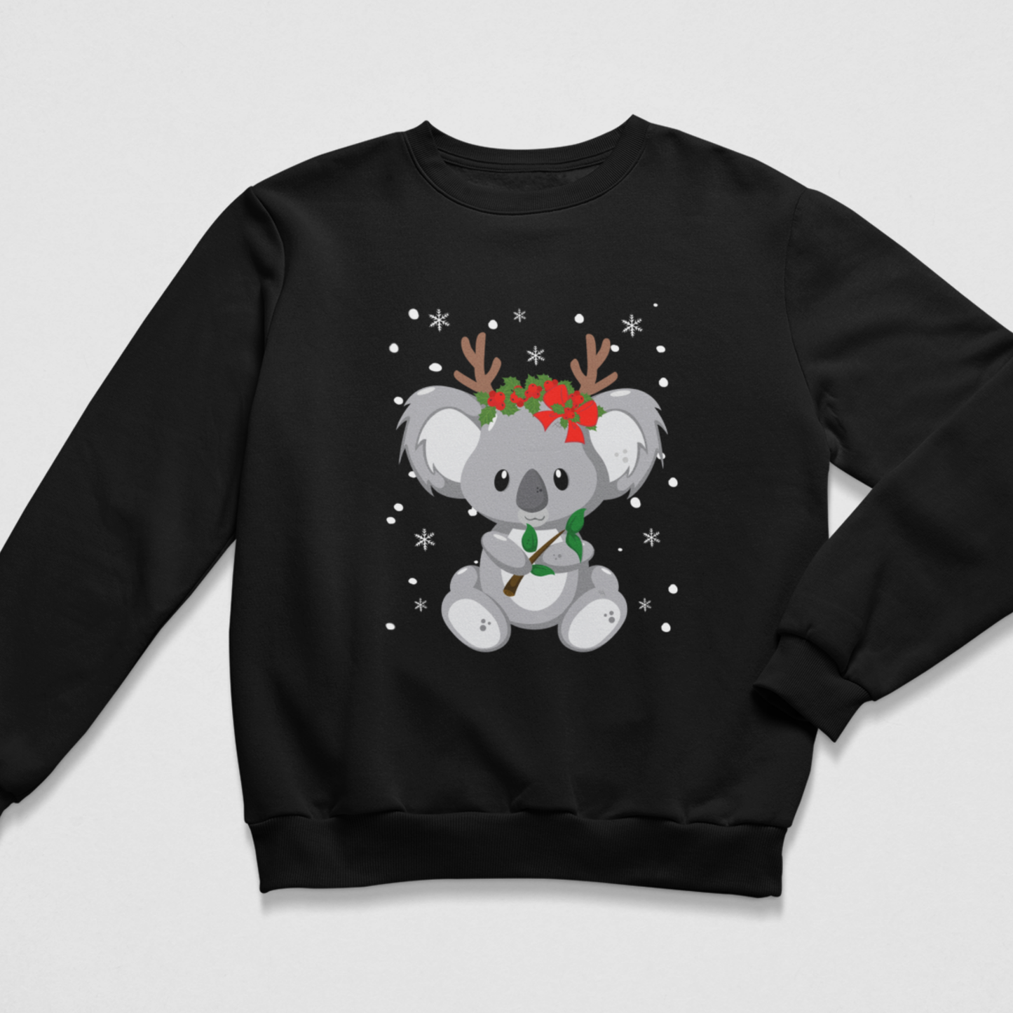 Children’s black Christmas sweatshirt with a centred koala bear design, red floral headpiece, antlers, leafy branch and white snowflakes for a festive winter look.