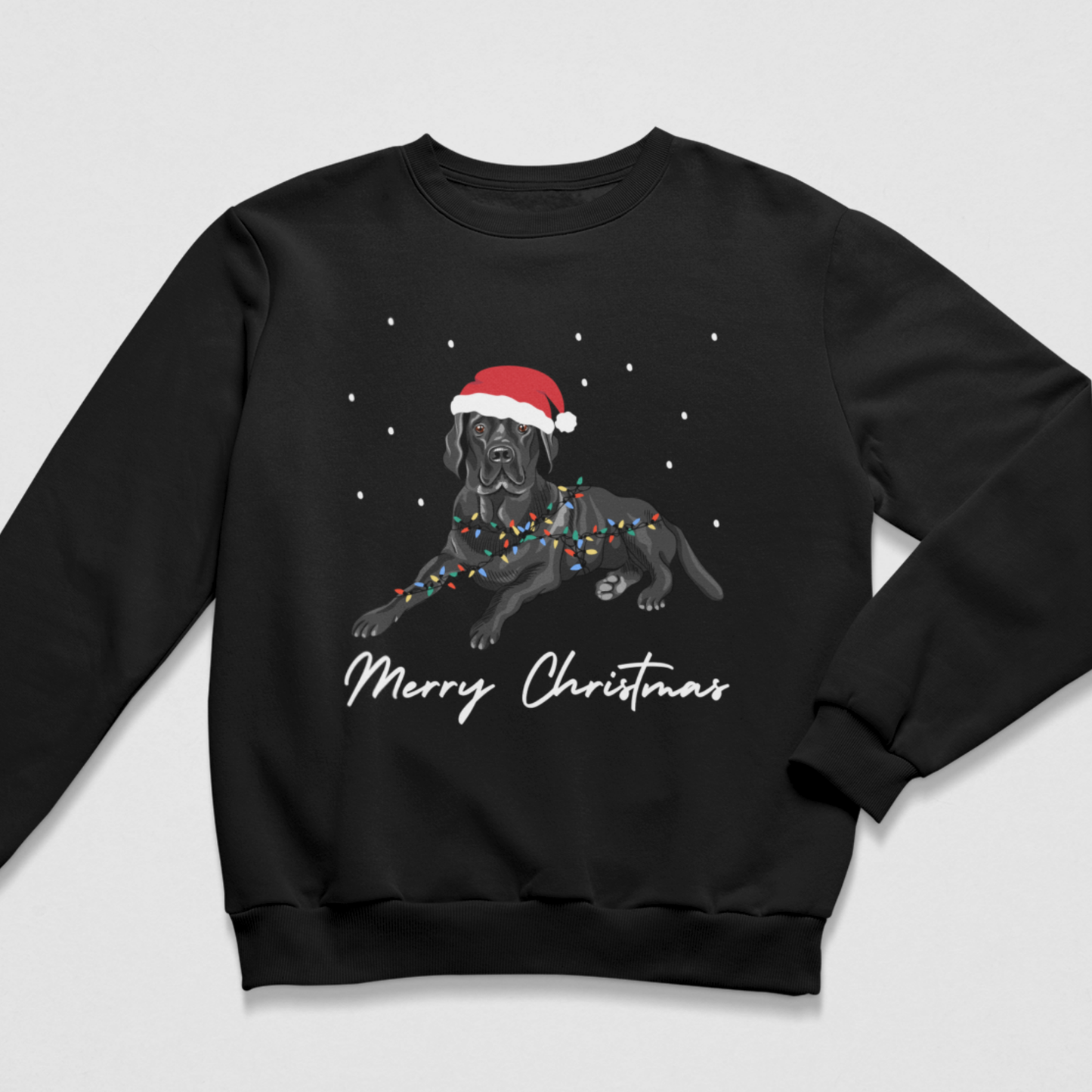 Kids Christmas sweatshirt in black featuring a black Labrador wearing a Santa hat, wrapped in colourful festive lights, with falling snow and white “Merry Christmas” script.