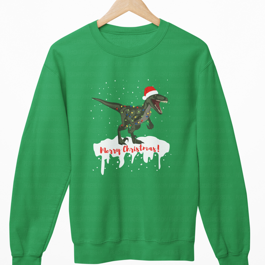 Kids Green Christmas jumper featuring a roaring T-Rex with Santa hat, fairy lights, snow, and “Merry Christmas” text