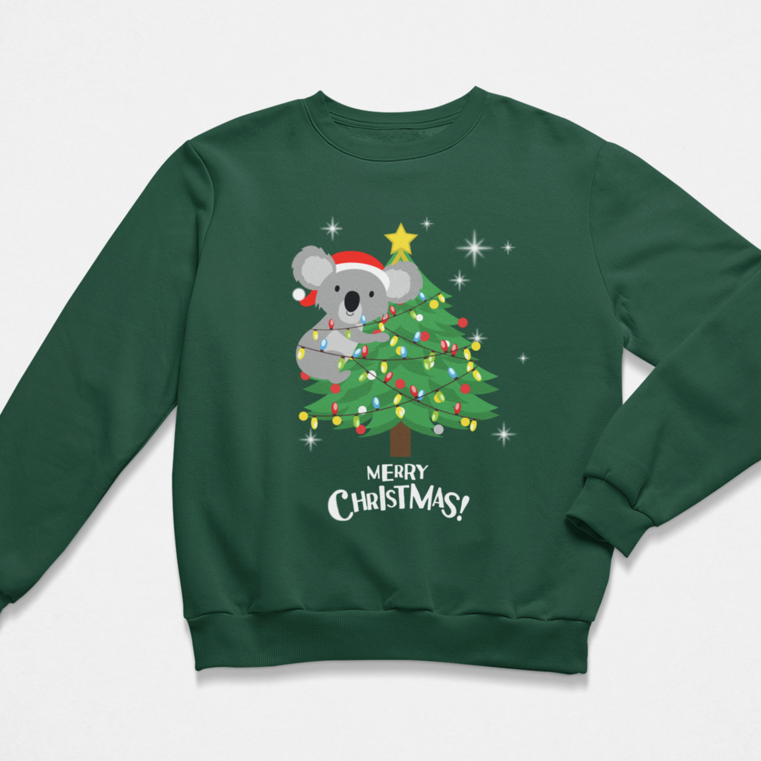 A children's dark green crewneck sweatshirt featuring a festive Christmas graphic of a grey koala wearing a red Santa hat next to a decorated green Christmas tree with a yellow star on top. Below the illustration, the text 'MERRY CHRISTMAS!' is printed in white.