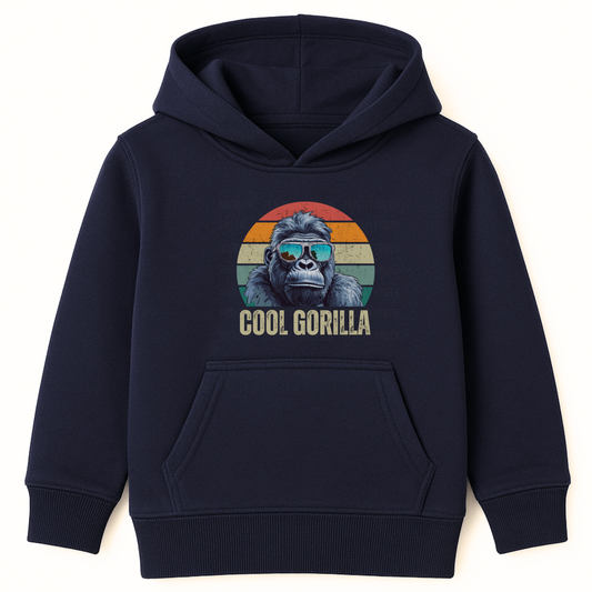 Kids navy pullover hoodie featuring a circular graphic of a cool gorilla in blue reflective sunglasses against a retro sunset background, with 'COOL GORILLA' text below. The boy has his hands in the hoodie's front pocket."