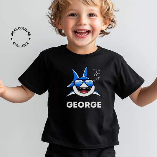 A child wearing a black cotton t-shirt with a printed shark design and the name 'George' on it.
