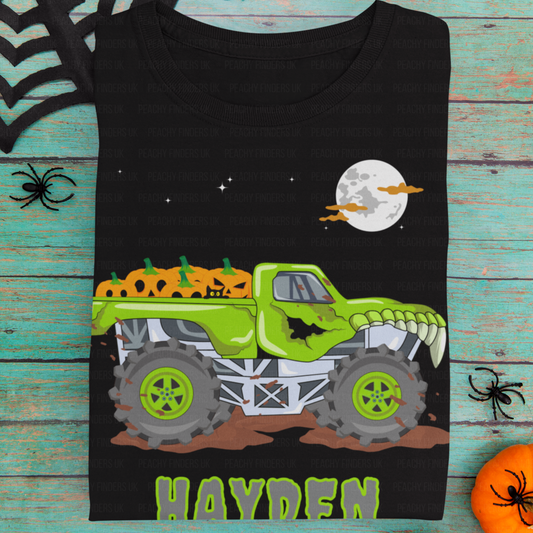 Black t-shirt with a green monster truck graphic and 'Hayden' text on a wooden surface.