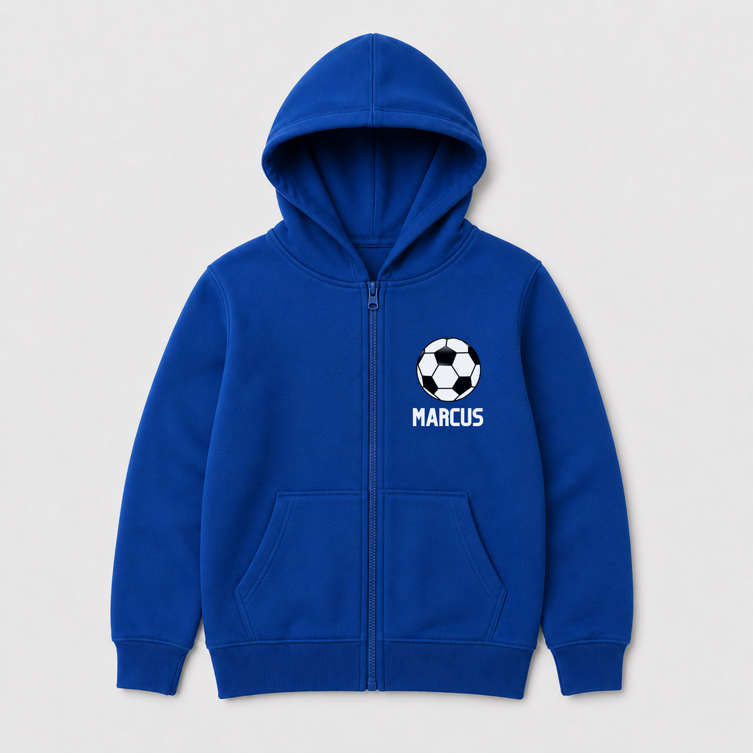 A royal blue zip-up hoodie for kids, featuring a white soccer ball graphic and the name 'MARCUS' printed in white on the left chest, displayed on a light gray background.