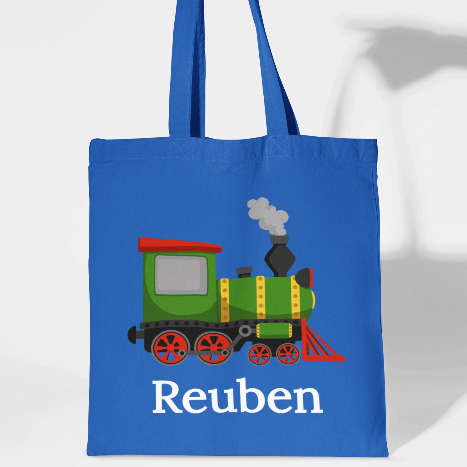 Kids blue tote bag with a green train design and 'Reuben' text on a white background