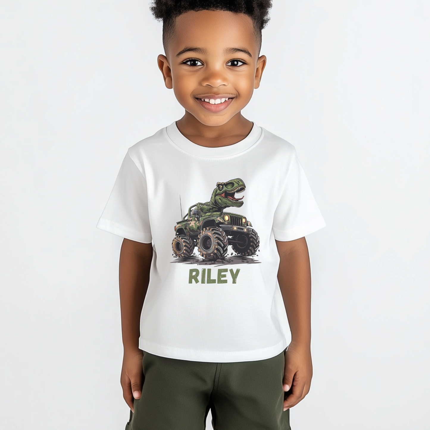 Smiling young boy wearing white personalised T-Rex monster truck t-shirt with name Riley.