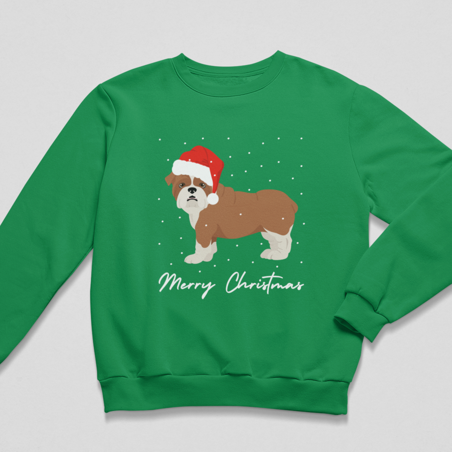 A kids green crewneck sweatshirt featuring a graphic of a brown and white dog wearing a red Santa hat, surrounded by white snowflakes, with 'Merry Christmas' written in white script below. The sweatshirt is displayed flat against a light grey background.