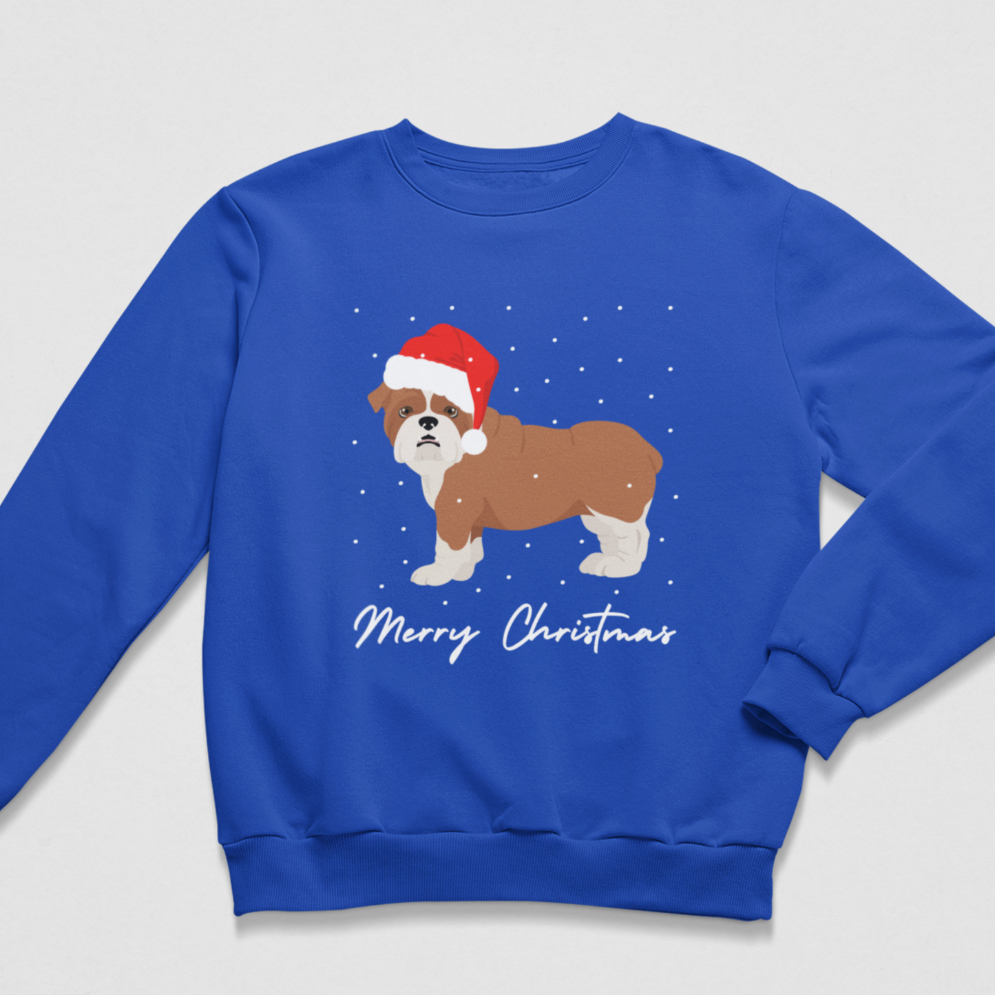 A kids royal blue crewneck sweatshirt featuring a graphic of a brown and white dog wearing a red Santa hat, with 'Merry Christmas' written in white script below, set against a light grey background.
