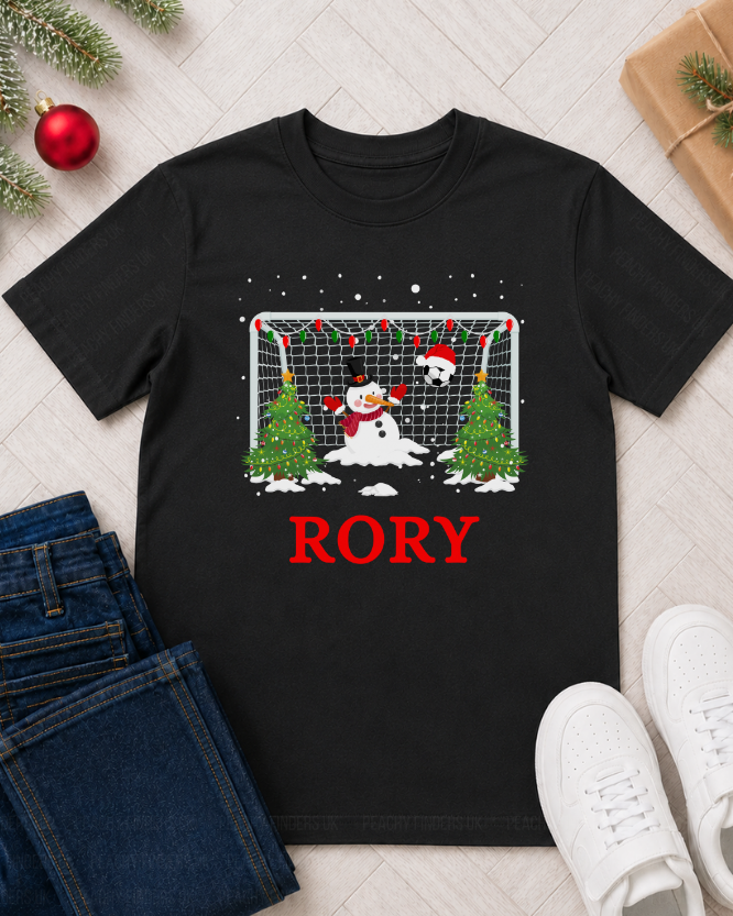 Kids personalised Christmas football T-shirt styled as a festive flat lay with jeans, trainers, bauble and wrapped gift.