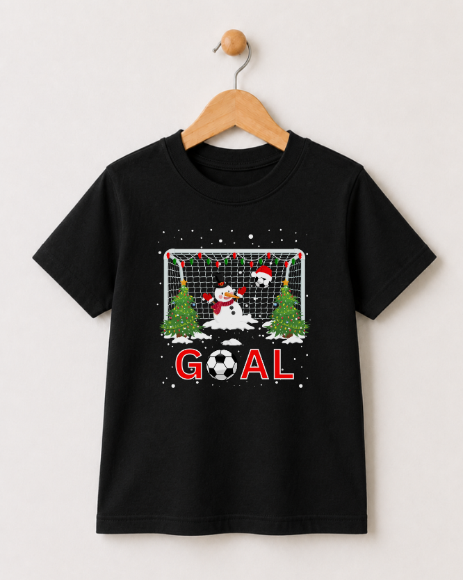 Children’s Christmas football T-shirt in black on a wooden hanger featuring a snowman goalie, festive football goal, Christmas trees and red GOAL text.