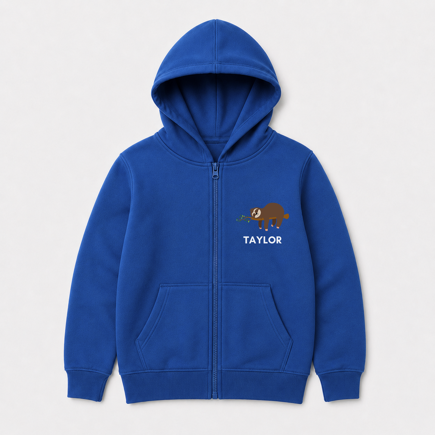 A kids royal blue zip-up hoodie with a front kangaroo pocket, featuring a small brown cartoon sloth graphic and the name 'TAYLOR' printed in white on the left chest, shown against a light grey background.