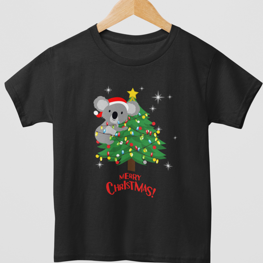 A kids black t-shirt with a graphic of a koala wearing a Santa hat climbing a Christmas tree, surrounded by festive lights, and the text 'Merry Christmas!' at the bottom.