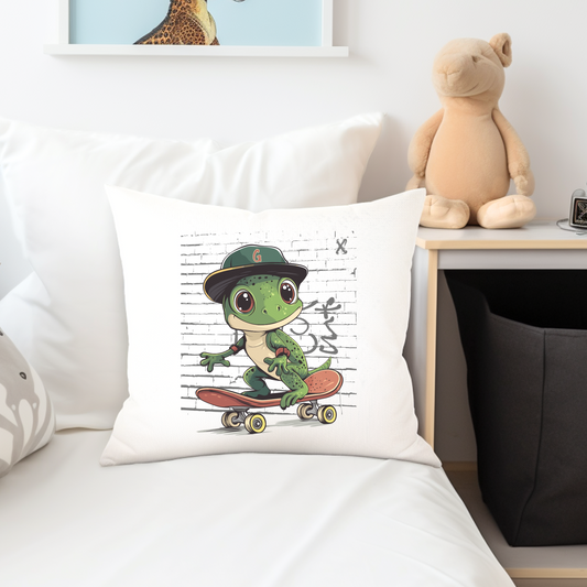 A cushion cover featuring an illustration of a green gecko wearing a hat and skateboarding, placed on a bed with a teddy bear on the side.