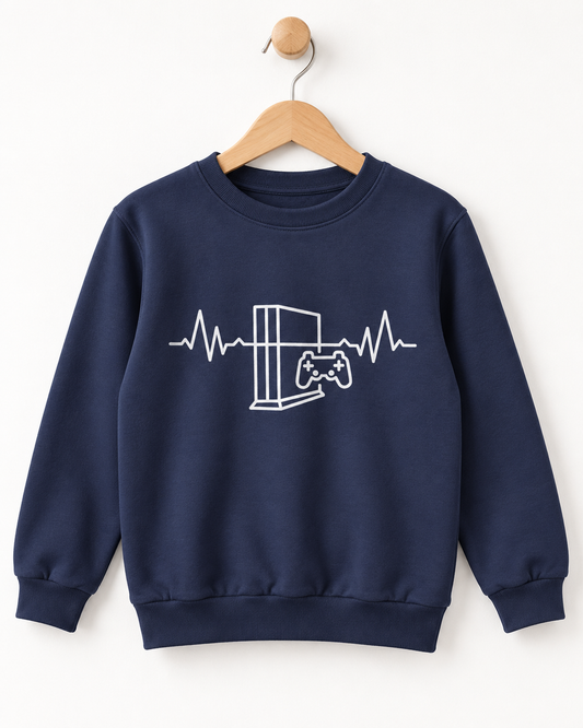 A navy blue crewneck sweatshirt hanging on a wooden hanger against a plain white wall. The sweatshirt features a white line art graphic of a video game console and controller integrated into an EKG heartbeat line across the chest.