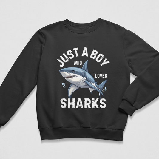 A kids black crewneck sweatshirt featuring a graphic print of a blue and white shark with the text 'JUST A BOY WHO LOVES SHARKS' in white, displayed on a light grey background.