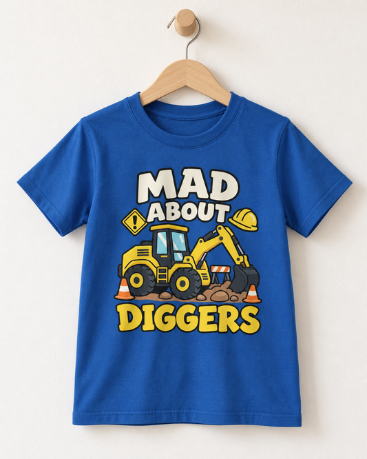 A royal blue kids' t-shirt hanging on a wooden hanger against a light beige wall. The shirt features a cartoon graphic of a yellow construction excavator with orange traffic cones and the text 'MAD ABOUT DIGGERS' in bold white and yellow letters.
