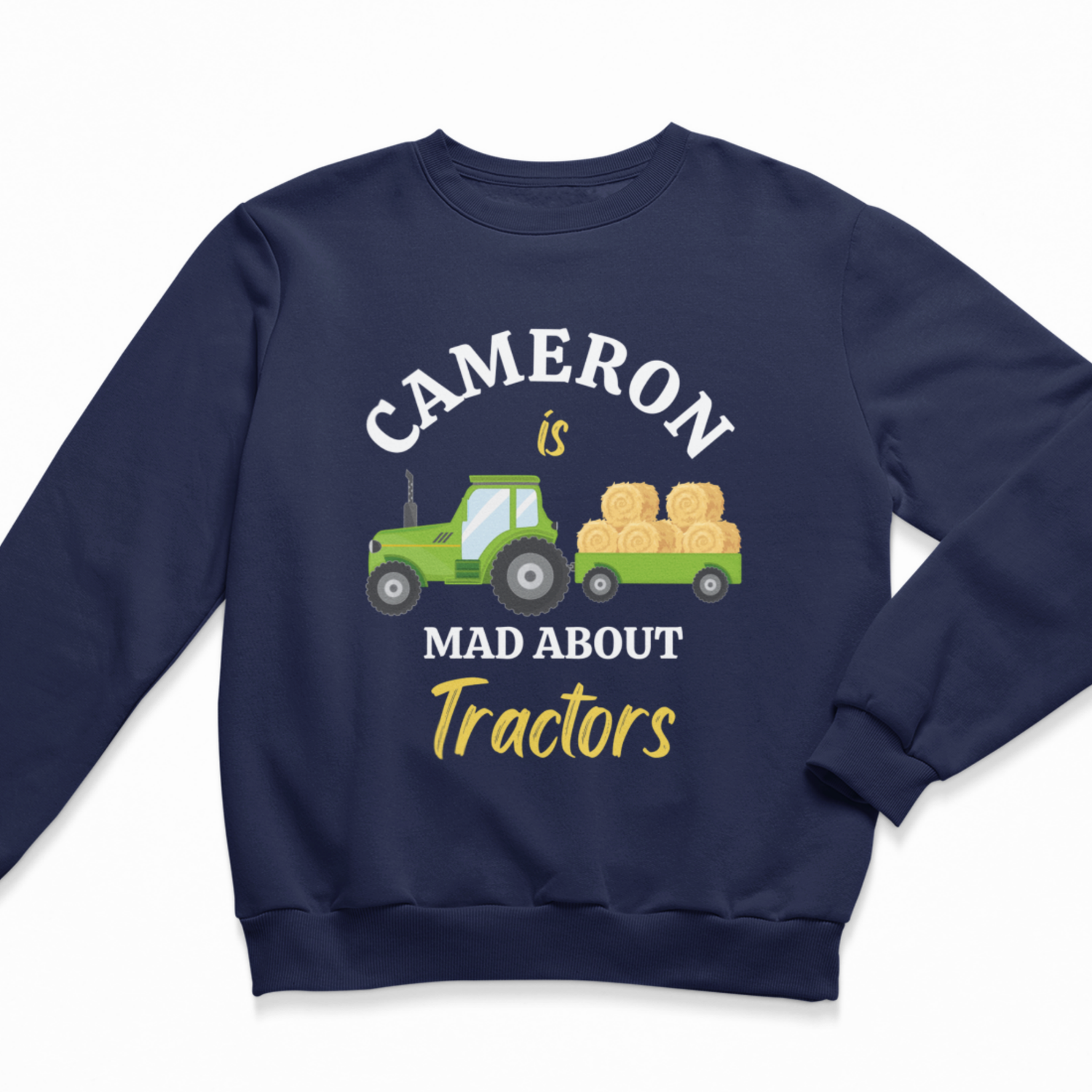 A kids navy blue crewneck sweatshirt featuring a graphic print of a green tractor pulling a trailer loaded with hay bales. The text reads 'CAMERON is MAD ABOUT Tractors' in white and yellow lettering.