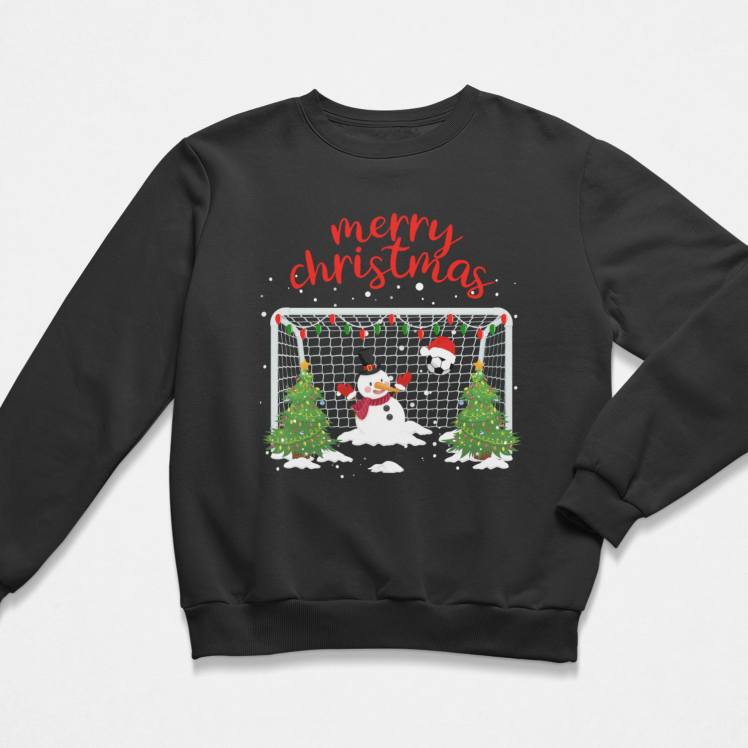 A kids black crewneck sweatshirt featuring a festive Christmas graphic on the front. The design includes the words 'merry christmas' in red script above a soccer goal scene with a snowman, a second snowman, two decorated Christmas trees, and falling snow details.