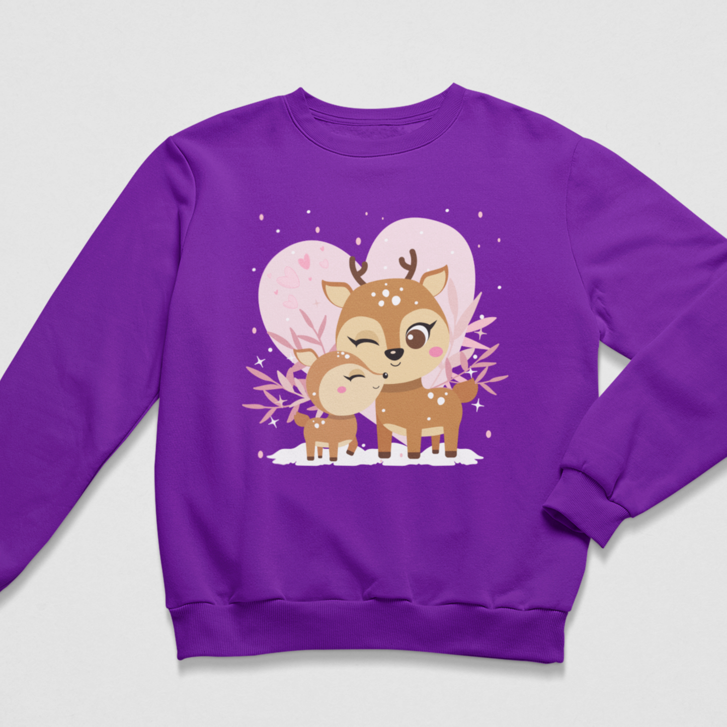 A girls purple crewneck sweatshirt featuring a cute cartoon graphic of mother deer and her fawn in the snow with pink hearts and white snow, displayed on a light grey background.