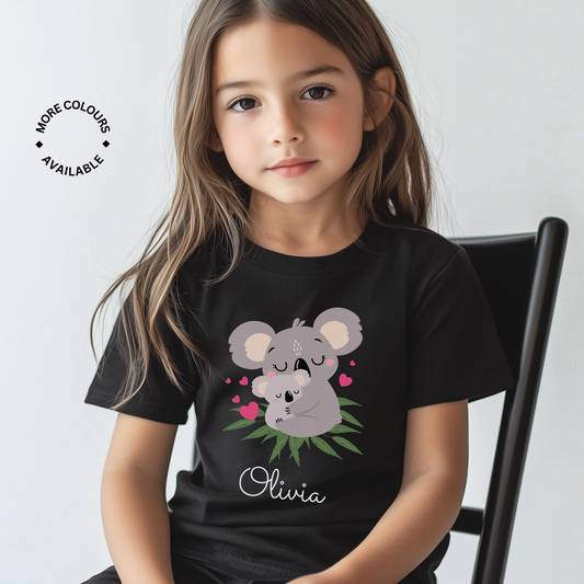 Little girl wearing a black personalised T-shirt with a cute mother and baby koala illustration and her name printed below in white script.