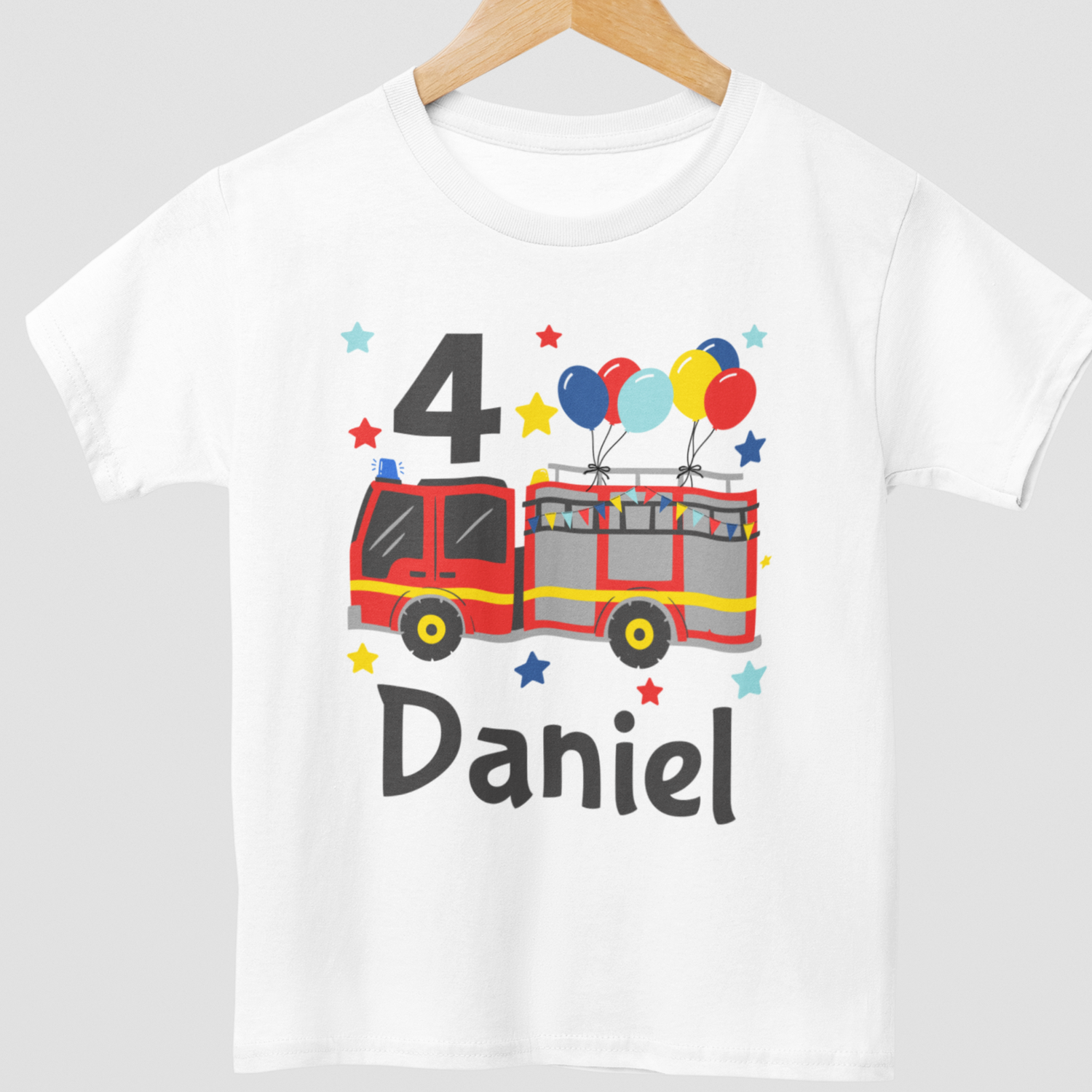 White children’s personalised 4th birthday fire engine T-shirt on wooden hanger with colourful balloons and custom name “Daniel”.