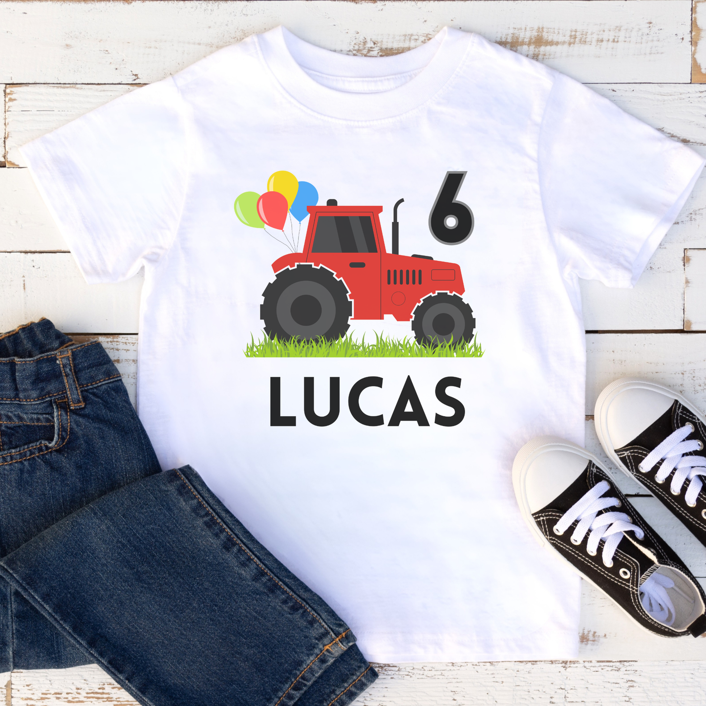 Personalised 6th birthday tractor t-shirt for boys with name Lucas, white tractor birthday shirt flat lay with jeans and trainers, kids birthday outfit idea