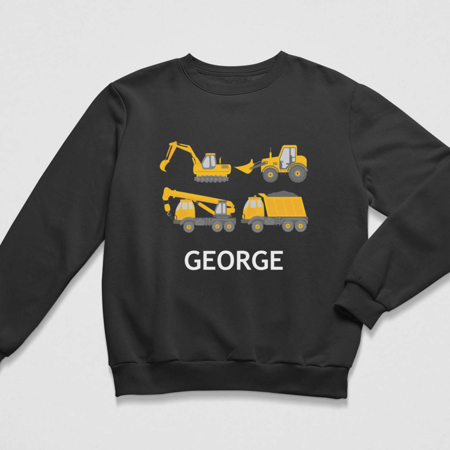 A kids black crewneck sweatshirt featuring a graphic print of yellow construction vehicles (excavator, bulldozer, tractor, crane, dump truck) with the name 'GEORGE' printed in white below them, displayed on a light grey background.