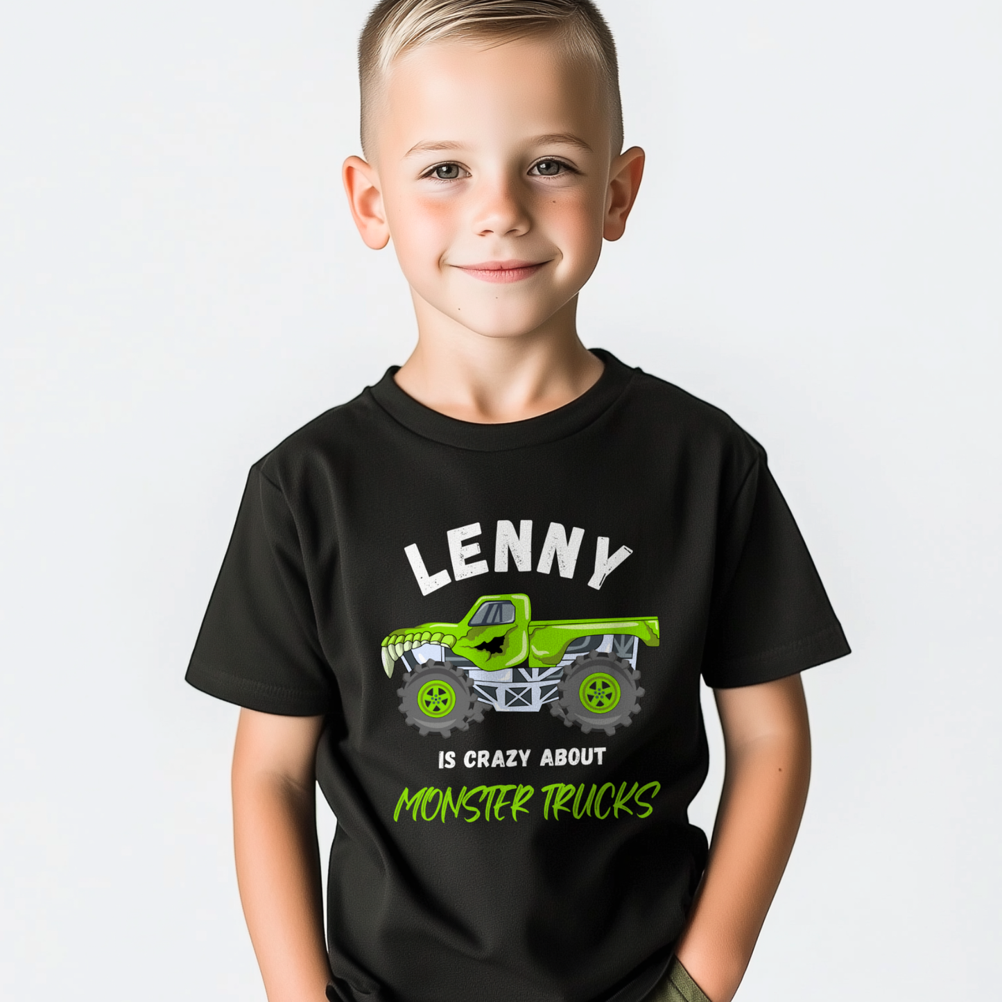 Smiling young boy wearing a black personalised ‘Lenny is crazy about monster trucks’ T-shirt with a bright green monster truck graphic on the front.