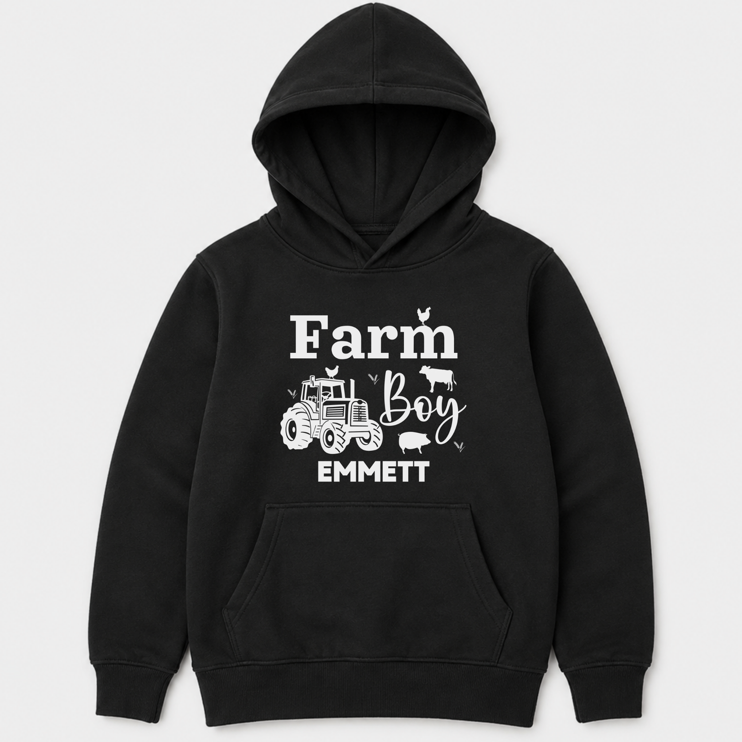 A kids black pullover hoodie with a white graphic print on the front that reads 'Farm Boy EMMETT' with a tractor and small farm animal illustrations, shown on a light grey background.