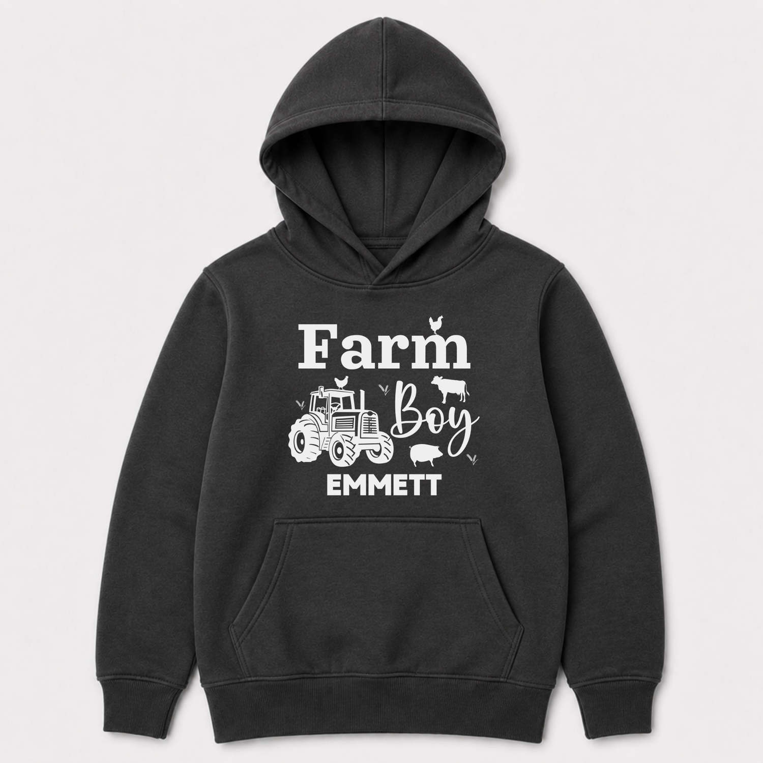 A dark grey pullover hoodie for kids with a white graphic print on the front that reads 'Farm Boy EMMETT' with illustrations of a tractor, cow, chicken, and pig, shown against a light grey background.