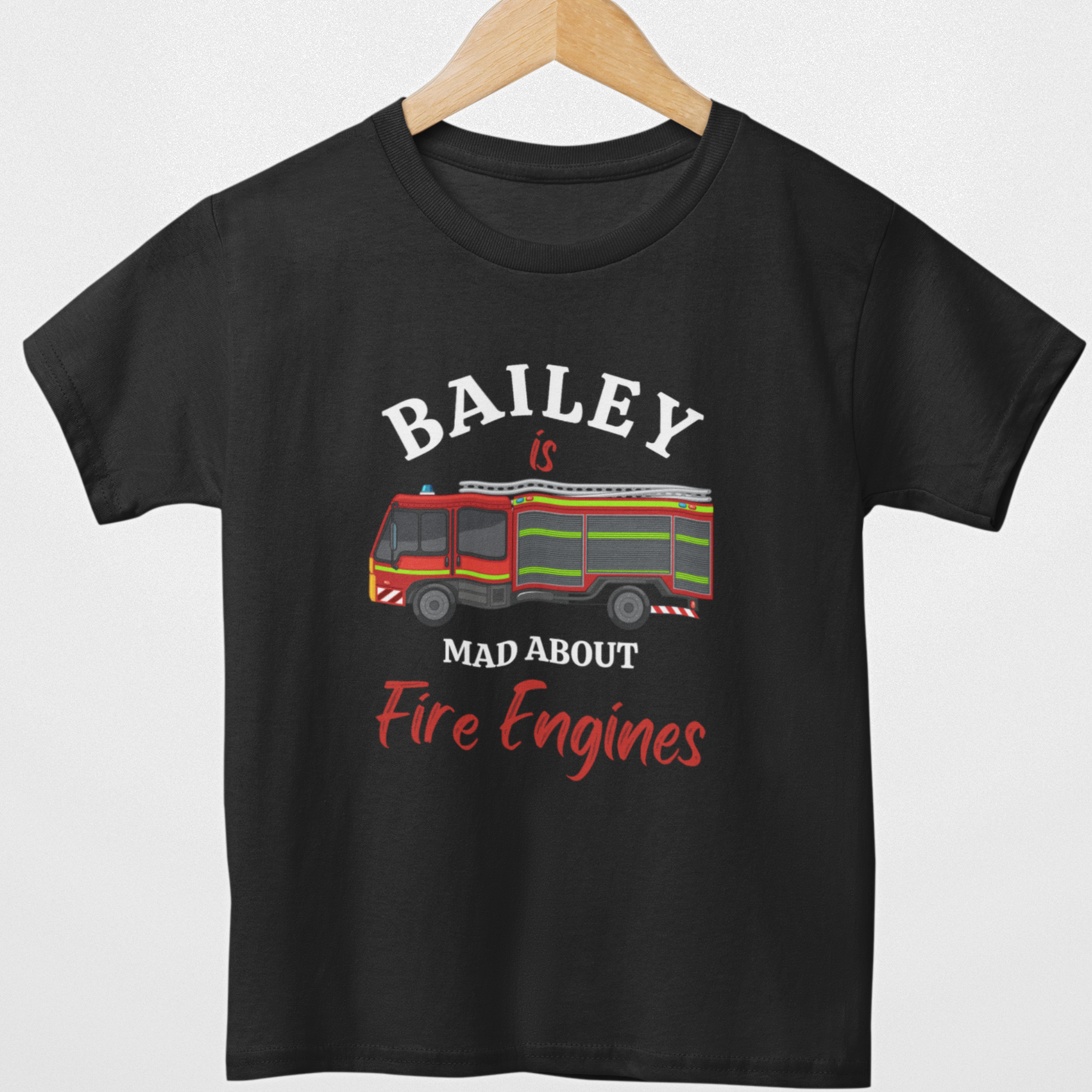 Kids black cotton t-shirt on hanger with red fire engine illustration and personalised text Bailey is mad about fire engines printed on the front.