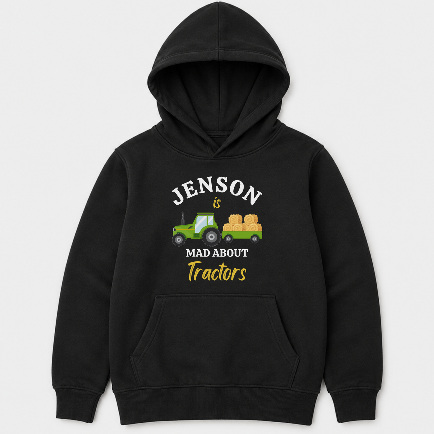 Children's black pullover hoodie with a front graphic that reads 'JENSON IS MAD ABOUT Tractors' in white and yellow text, featuring a small green tractor and hay bale illustration, shown on a light grey background.