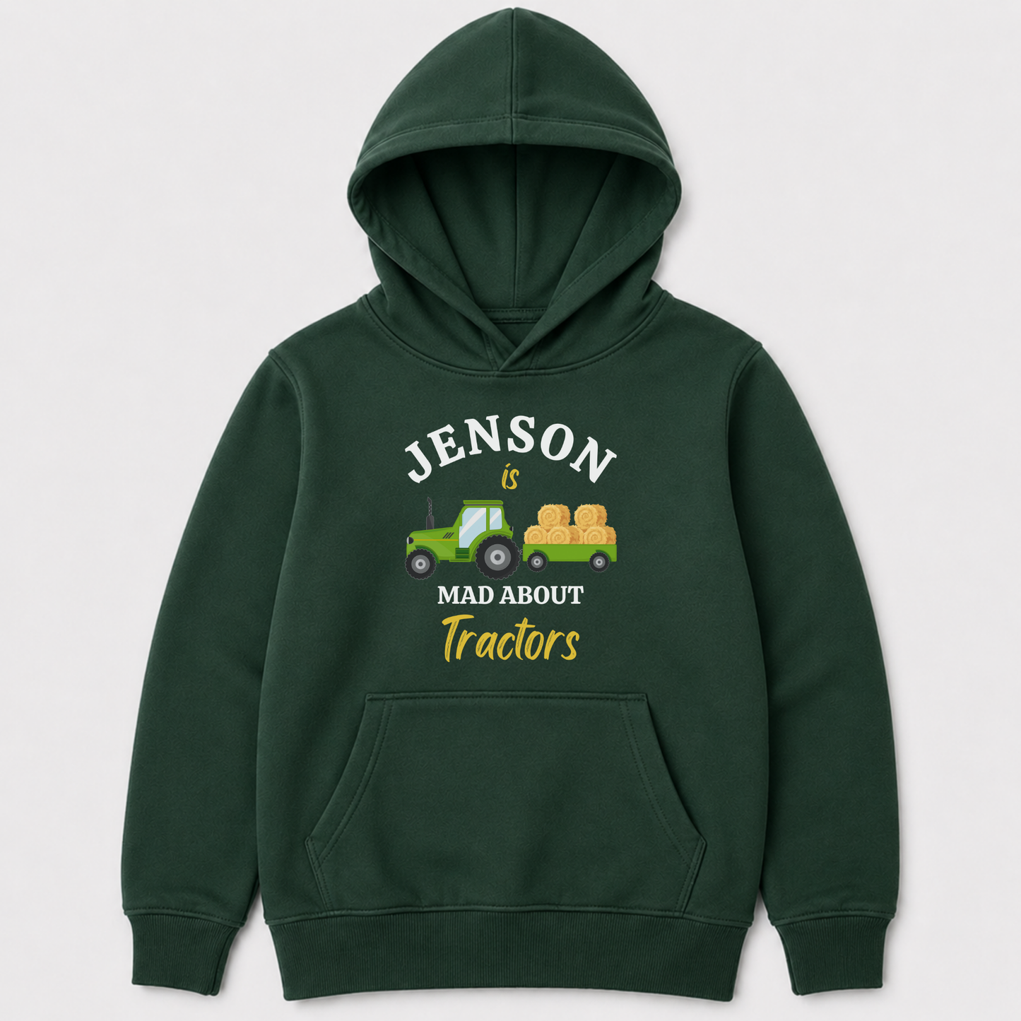 A dark green kids pullover hoodie with a front graphic that reads 'JENSON is MAD ABOUT Tractors' in white and yellow text, featuring a small green tractor and hay bale illustration. The hoodie is shown against a light grey background.
