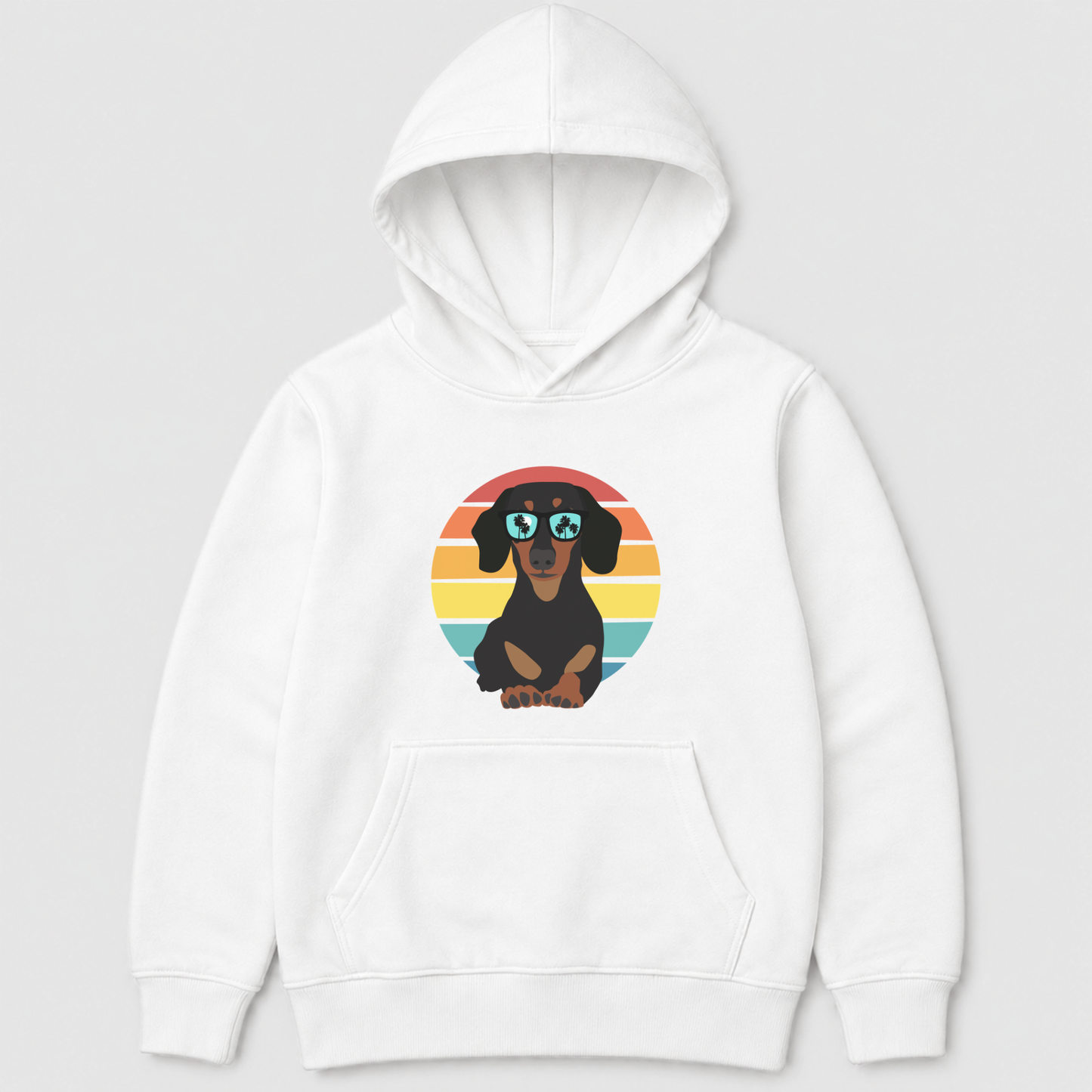 A kids white pullover hoodie featuring a cartoon dachshund wearing round sunglasses, set against a retro sunset circle graphic on the chest, displayed on a neutral light grey background.