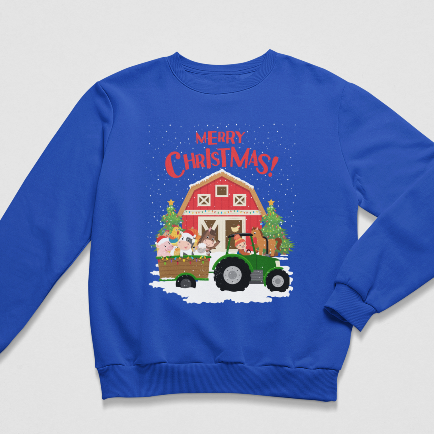 Flat lay of a royal blue children's Christmas crewneck jumper displaying a green tractor with a trailer of festive farm animals in front of a red barn and Christmas trees