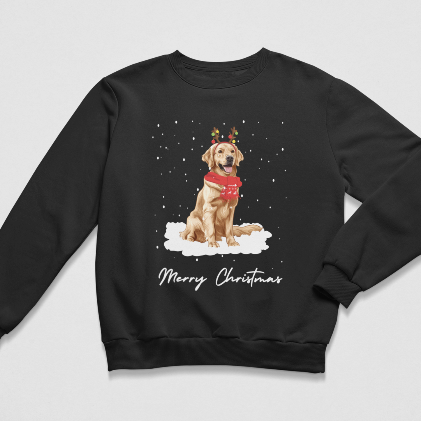 A black crewneck sweatshirt featuring a graphic of a golden retriever dog wearing a red sweater and reindeer antlers, sitting on snow with 'Merry Christmas' written below in white script, shown on a light grey background.