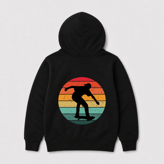 A kids black hoodie shown from the back, featuring a large circular graphic of a skateboarder's silhouette against a retro sunset gradient background.