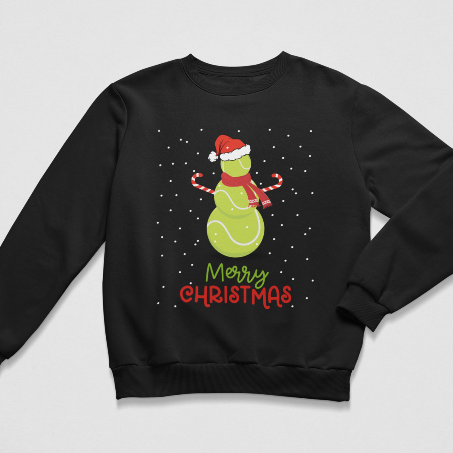 A kids black crewneck sweatshirt featuring a festive graphic of a green tennis ball snowman with a red Santa hat candy cane arms and scarf, surrounded by white snowflakes, with 'Merry Christmas' written below in green and red.