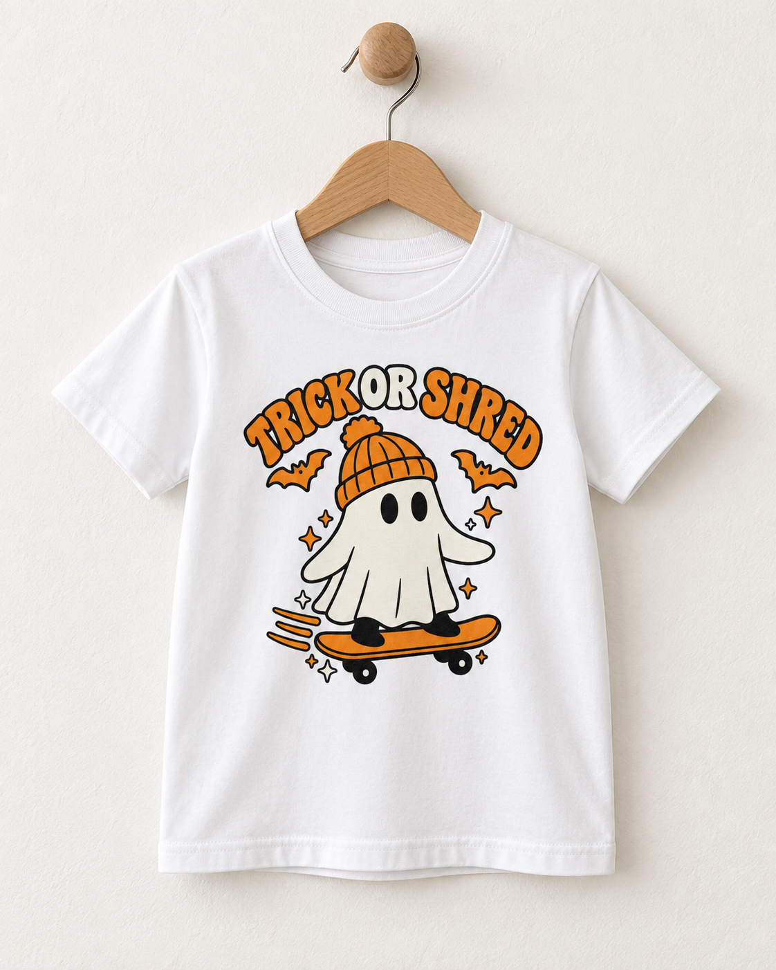 White kids Trick or Shred skateboarding ghost Halloween T-shirt displayed on a wooden hanger