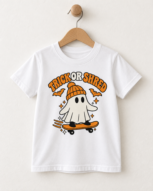 White kids Trick or Shred skateboarding ghost Halloween T-shirt displayed on a wooden hanger