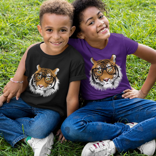 A boy and a girl sitting on grass wearing kids t-shirts featuring a tiger wearing glasses - one in black and one in purple - showing a fun, clever animal design.
