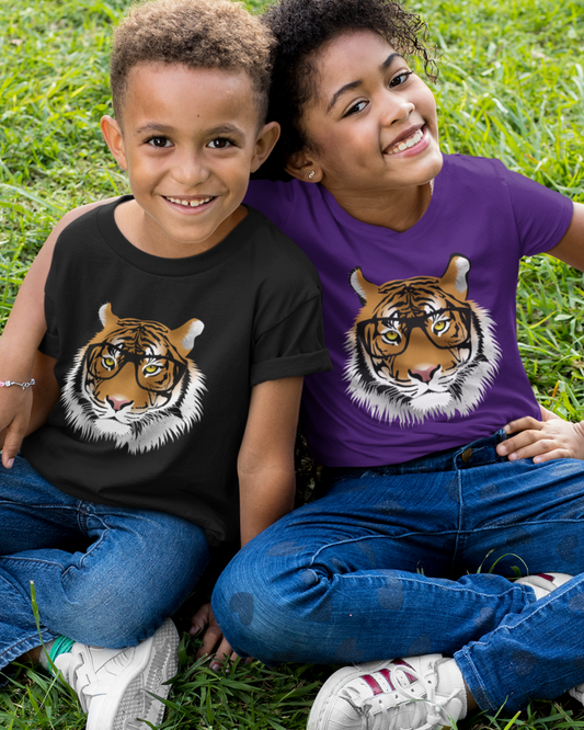 A boy and a girl sitting on grass wearing kids t-shirts featuring a tiger wearing glasses - one in black and one in purple - showing a fun, clever animal design.