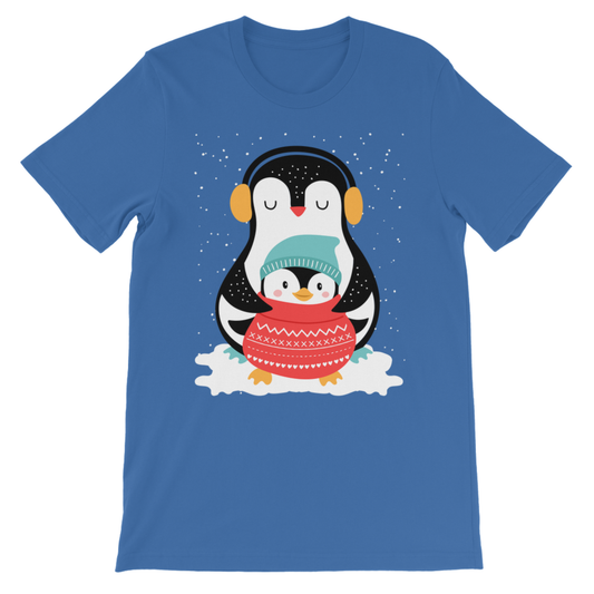 Children's blue short-sleeve crewneck t-shirt featuring a cartoon penguin graphic on the front. The penguin illustration shows a larger black and white penguin wearing yellow headphones and hugging a smaller penguin wrapped in a red knit sweater, with white snow details around them.
