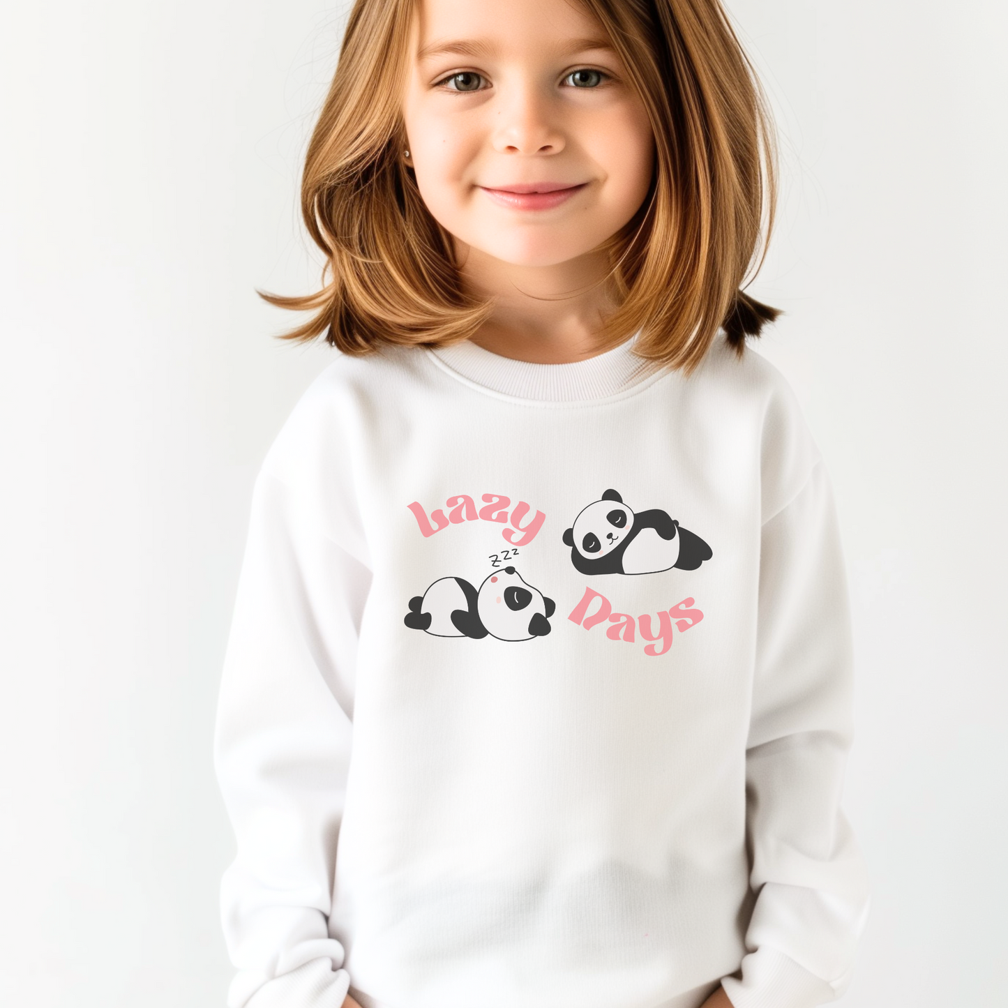 Young girl smiling in a white sweatshirt with a "lazy days" panda design.