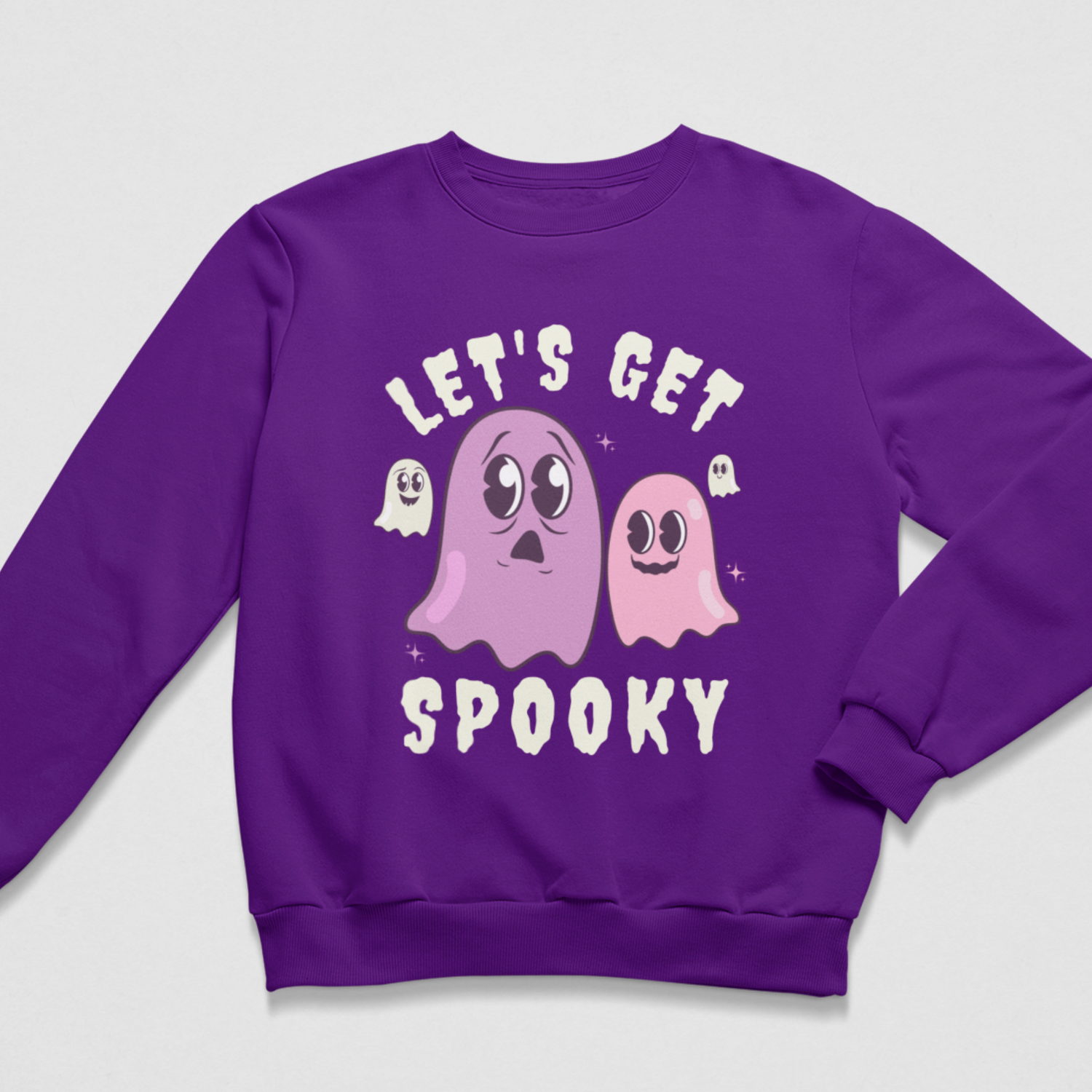 Purple women’s Halloween sweatshirt featuring pink and lilac cartoon ghosts with cream “Let’s Get Spooky” lettering.