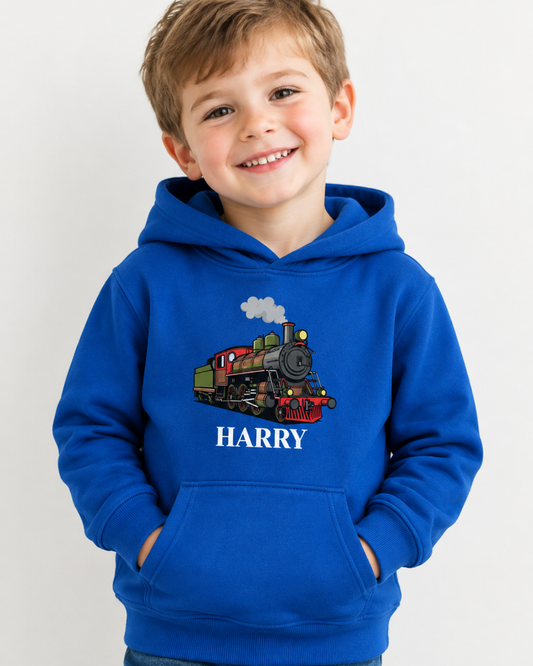 A smiling young boy wearing a royal blue hoodie with a graphic of a vintage train and the name 'HARRY' printed on the front, set against a plain light gray background.
