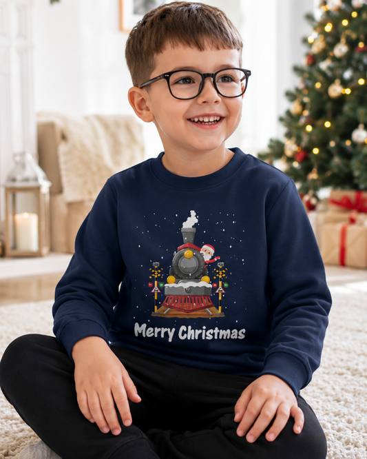 Young boy wearing a navy Santa steam train Christmas jumper with Merry Christmas text in a bright festive living room.