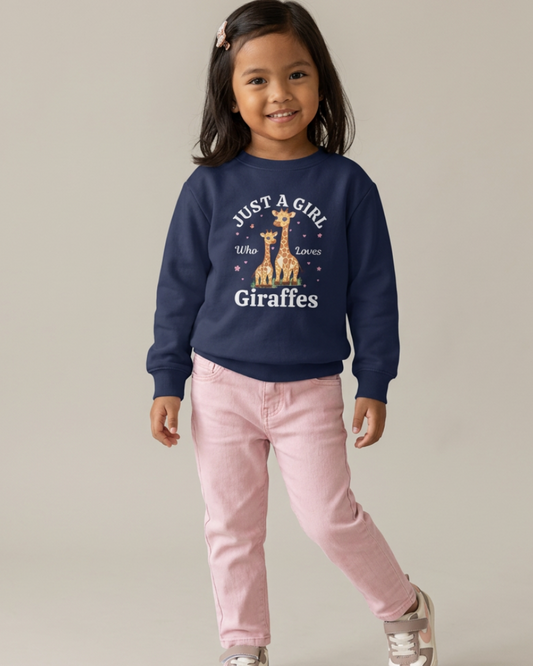 Young girl with dark hair wearing a navy blue crewneck sweatshirt with a cute giraffe design and the text "Just a Girl Who Loves Giraffes," paired with light pink trousers and trainers