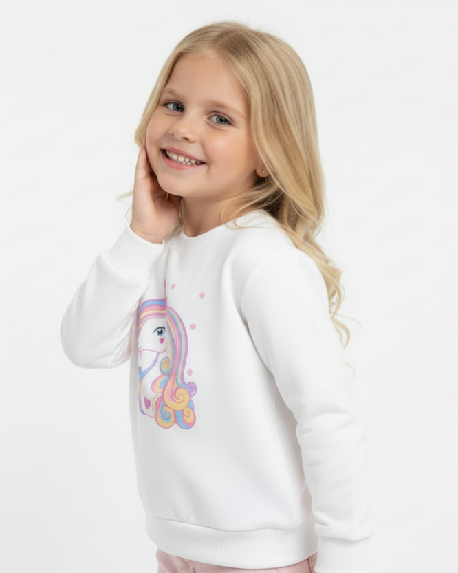 Girl wearing white unicorn sweatshirt with rainbow design side pose