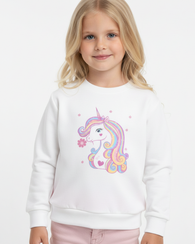 Little girl wearing a white sweatshirt featuring a pastel rainbow unicorn with long colourful mane and a pink flower by its mouth, surrounded by small flower accents.